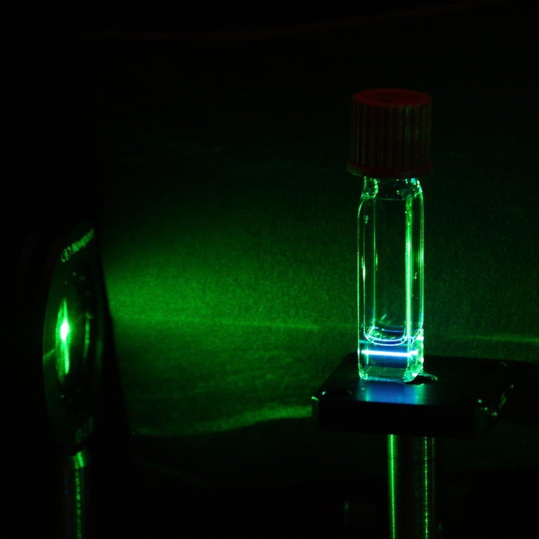 A green laser light going through the silicon quantum dots, and the silicon quantum dots re-emitting blue light (i.e. upconversion).